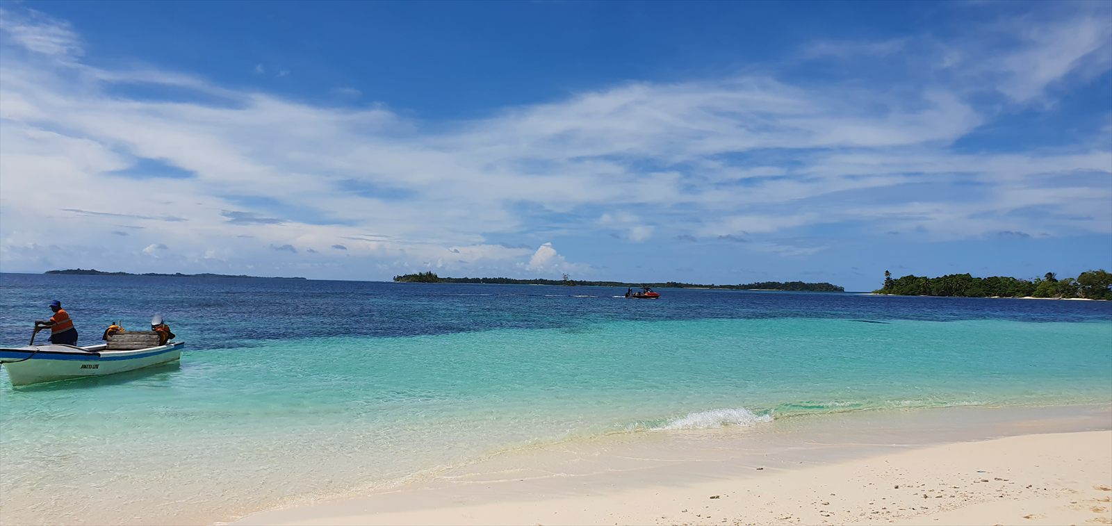 White sand beach and turquoise water in the Arnavon Islands, with a small boat close to shore