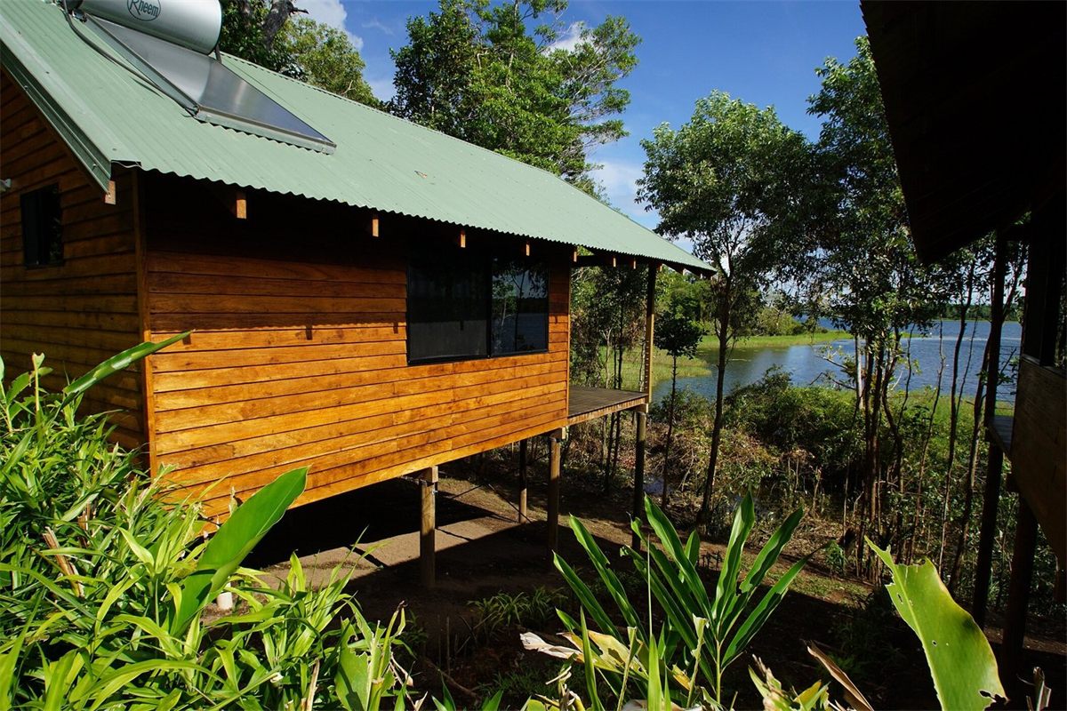 A timber cabin on stilts among the trees at Lake Murray Lodge, with the lake beyond