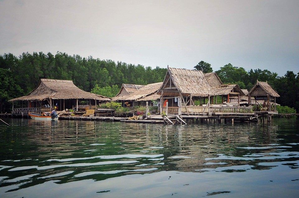 Marovo Sea Lodge’s leaf-thatched buildings on stilts over the water, backed by forest