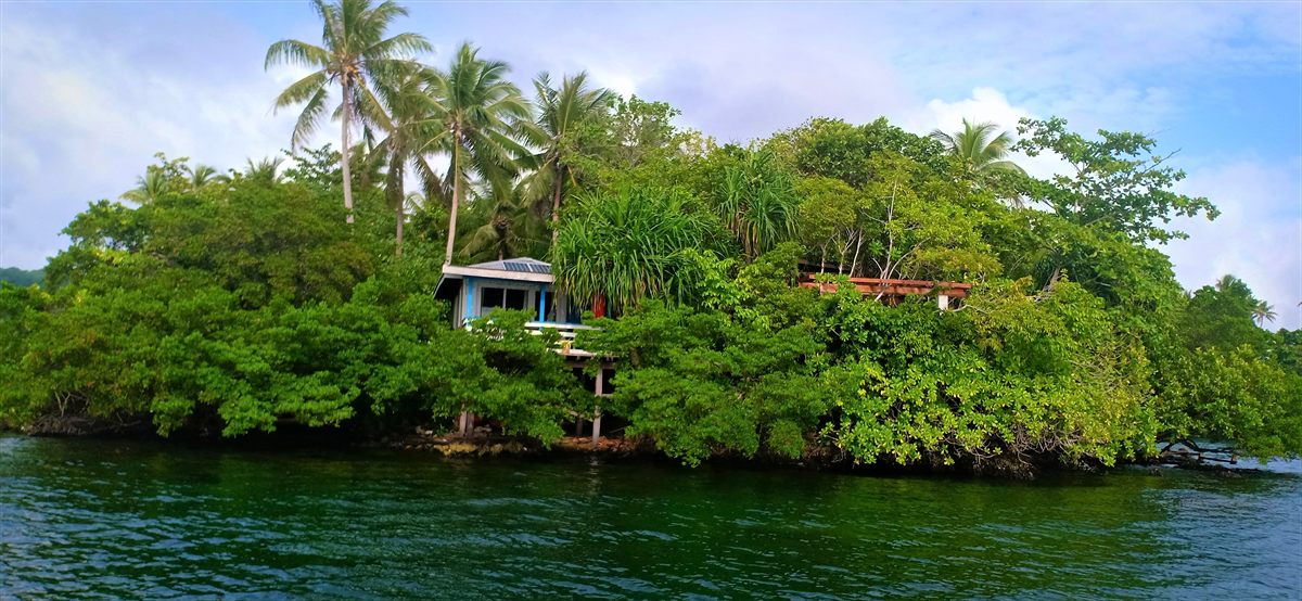 Bungalow East, a blue-trimmed bungalow half hidden in the islet’s trees above the lake