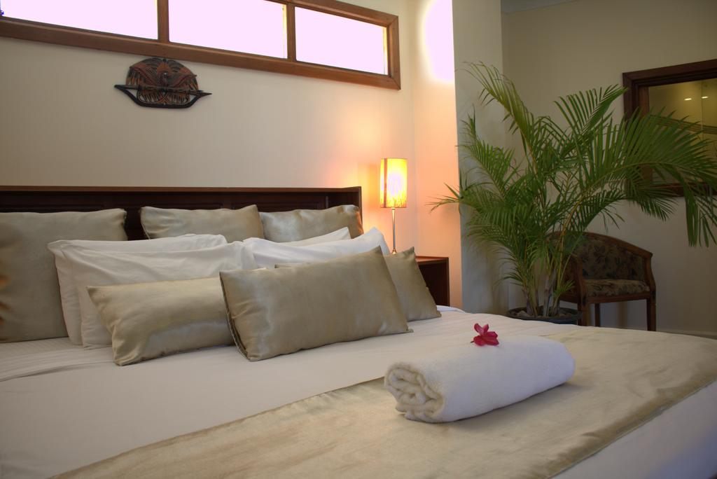 A made-up bed with a hibiscus flower on a folded towel in a room at Rapopo Plantation Resort