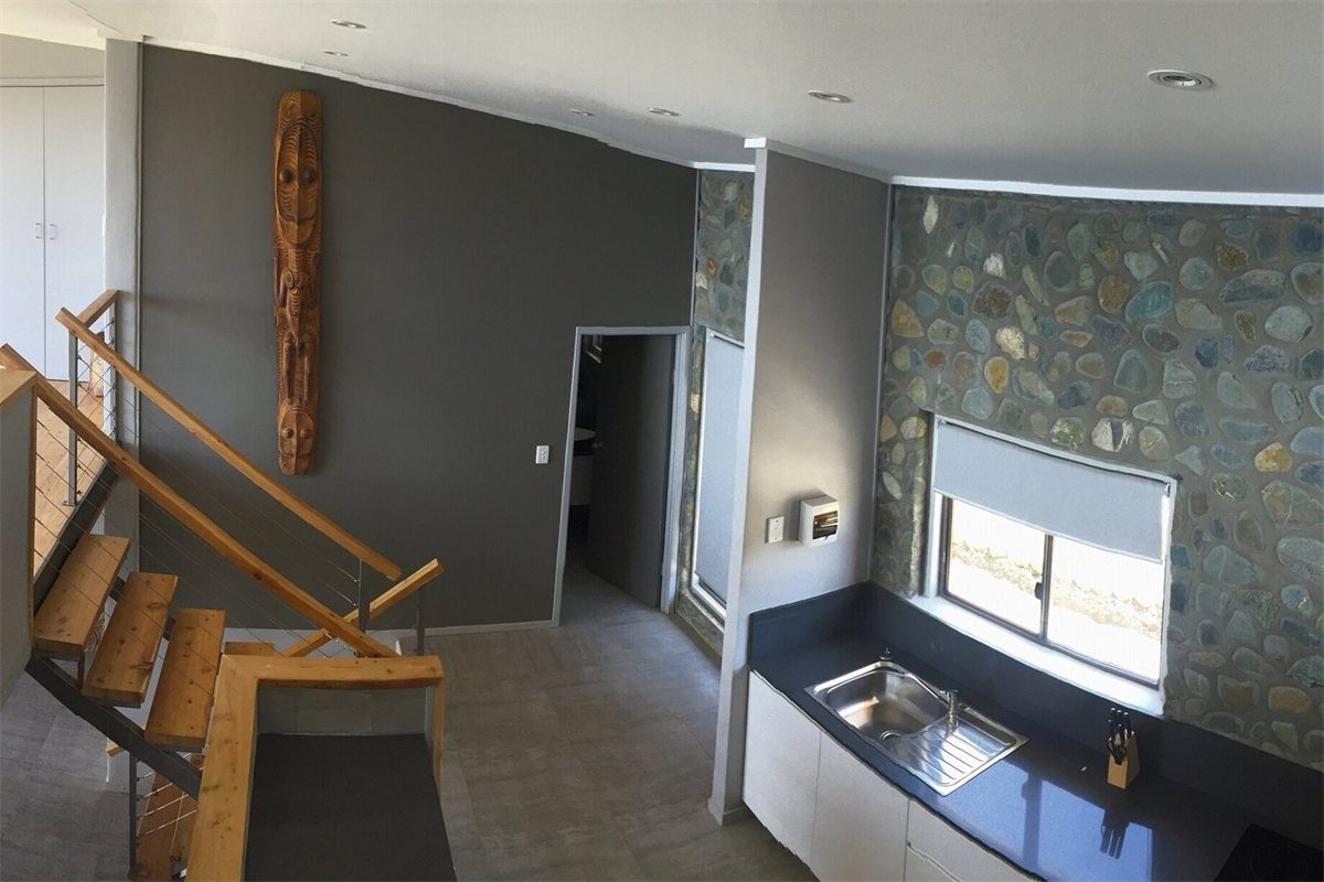 Inside a room at Rondon Ridge — timber stairs, a tall carved wooden figure and a kitchenette under a stone feature wall