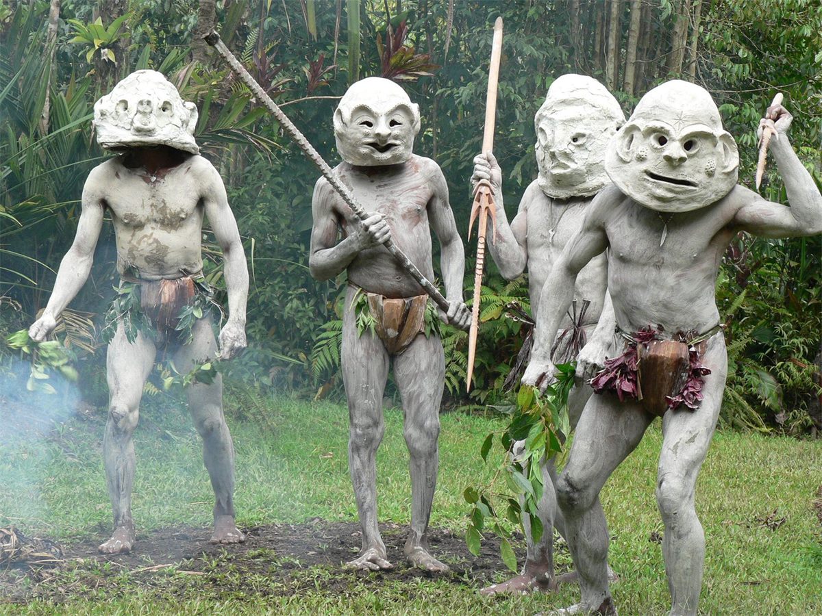 Highland performers in white clay masks and body clay, carrying spears — the famous mudmen of the PNG highlands