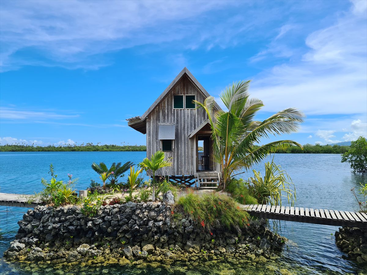 A timber bungalow on its own small stone-walled island, joined by boardwalks across the lagoon