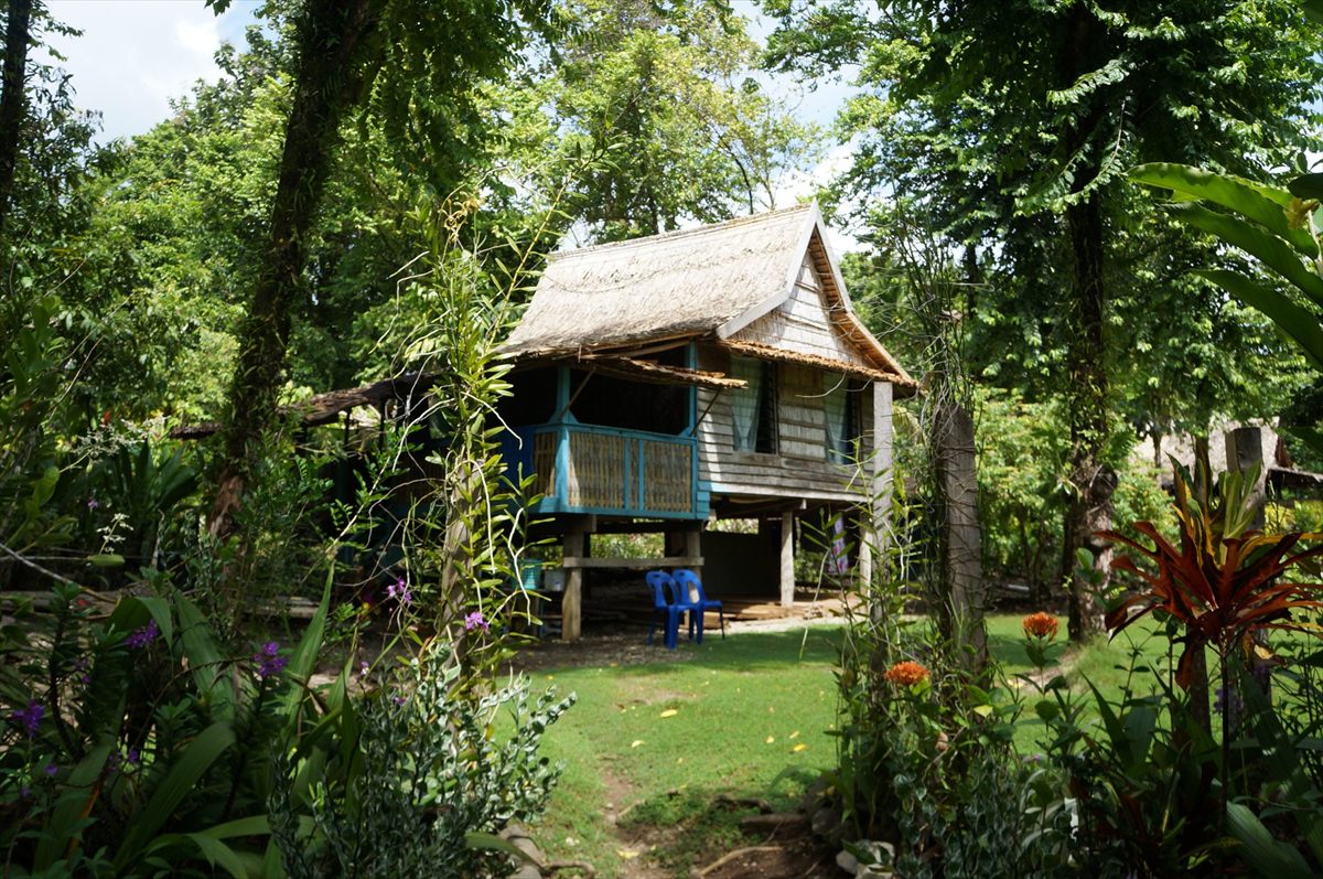Takapuna Rest House, a leaf-roofed house on stilts in a tropical garden on Ranongga Island
