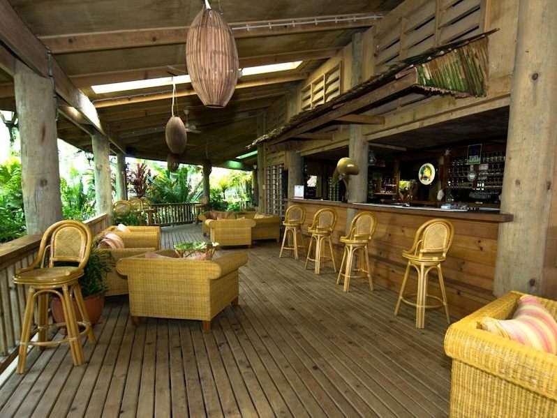 Cane bar stools and lounge chairs on the covered timber bar deck at Tufi Resort